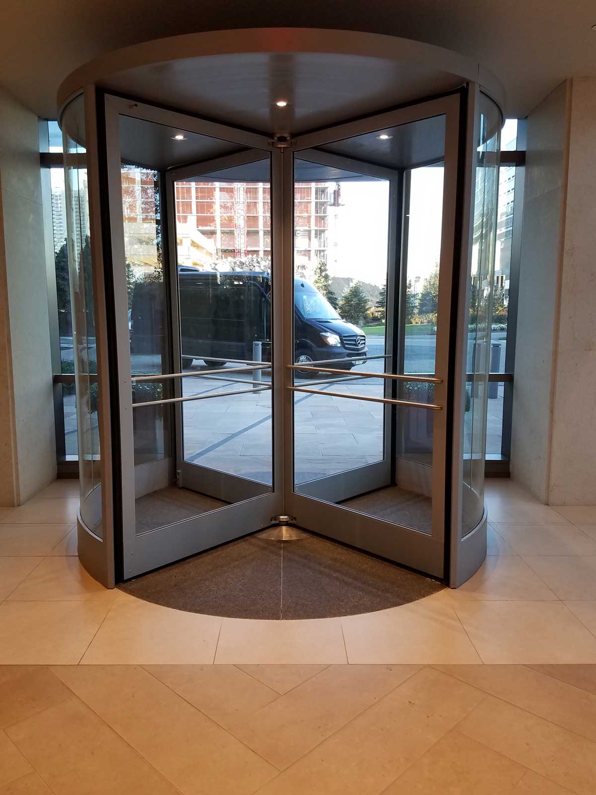 Exterior revolving door entrance at a commercial high-rise building in an urban setting